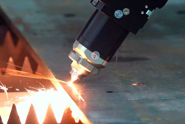 Detalle de cabezal de corte láser de fibra manteniendo precisión milimétrica en acero inoxidable.